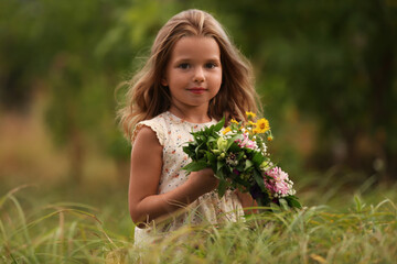 Naklejka na ściany i meble Cute little girl holding wreath made of beautiful flowers in field