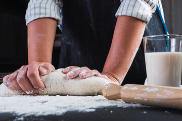 Hands shaping the dough on a wooden counterpart filled with flour.