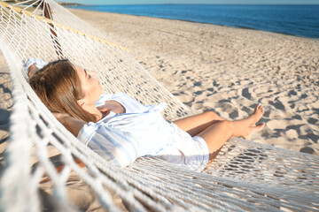 Young woman relaxing in hammock on beach