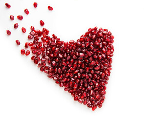 Heart from a pomegranate on a white background. Valentine's card. Broken heart. Pomegranate berries are scattered.