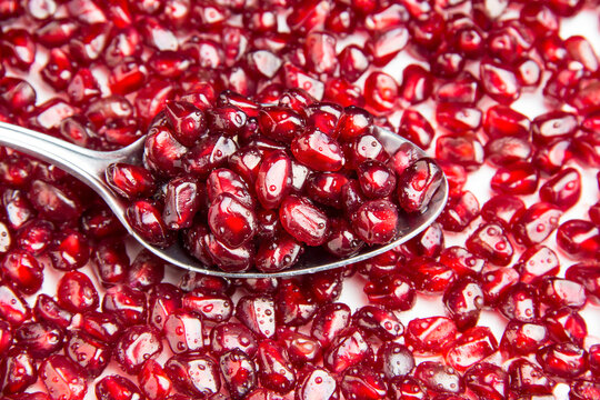 A tablespoon with pomegranate berries. Delicious berries.