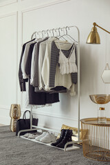 Rack with stylish clothes near white wall in dressing room