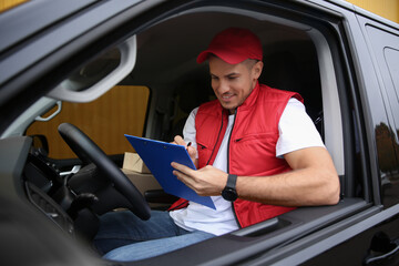 Courier with clipboard on driver's seat of car