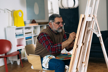senior man painting the picture at his home