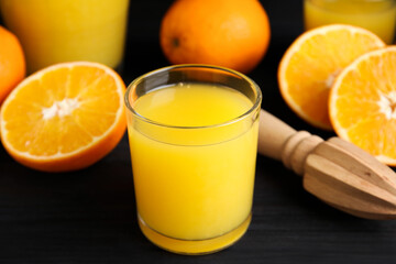 Fresh ripe oranges, juice and reamer on dark wooden table, closeup
