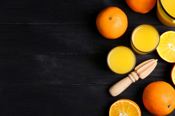Fresh ripe oranges, juice and reamer on dark wooden table, flat lay. Space for text