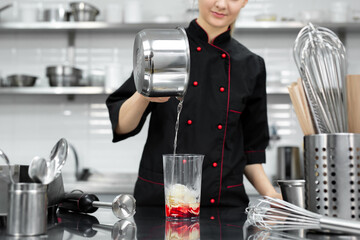 Pastry chef whips up the red mirror icing for the cake with a blender.