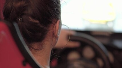 Little girl playing racing simulator game in theme park