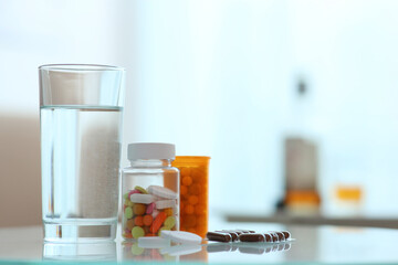 Glass of water and pills on table indoors, space for text. Hangover remedy