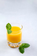 Fresh oranges and orange juice in glasses on an orange background. Mint leaves. Still life. Close up. Copy space.