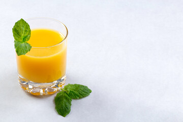 Fresh oranges and orange juice in glasses on an orange background. Mint leaves. Detox. Close up. Copy space.