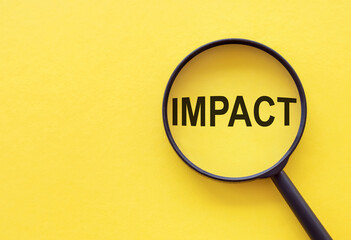 The word IMPACT is written on a magnifying glass on a yellow background.