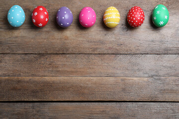Obraz na płótnie Canvas Colorful eggs on wooden background, flat lay with space for text. Happy Easter