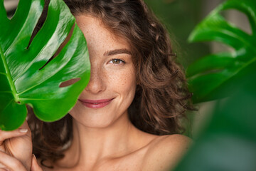 Beauty natural woman covering her face with tropical leaf - obrazy, fototapety, plakaty