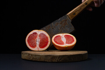 Grapefruit on a black background. A grapefruit cut in half with an ax. Citrus fruit. Exotic fruit