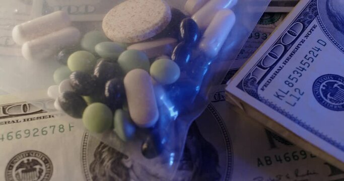 Drugs in plastic bag on top of 100 Dollar Bills. Buying Drugs and medicine. Illegal Drugs and Steroids in different colors, on Large Banknotes
