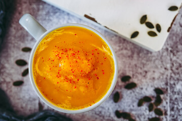 Soupe de courge au curry et baies roses dans un bol sur un fond couleur béton