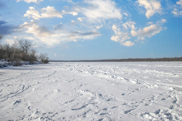 Fototapeta na wymiar View down sa snow covered frozen river shoreline on both sides sunny with clouds nobody
