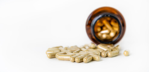 Herbal medicine capsules spilling out of a bottle.