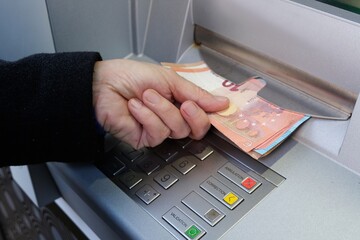 Gros plan sur quelqu'un retrait des billets de banque en euro d'un distributeur automatique - obrazy, fototapety, plakaty