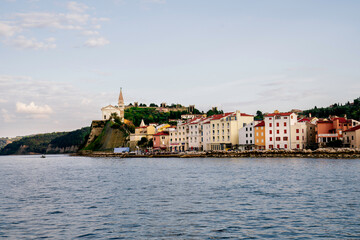 Fototapeta na wymiar Piran at sunset, view from the sea toward the old town and church Slovenia, Europe