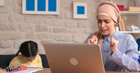 Headscarved woman working at home at the computer is making a mistake. The woman who made the...