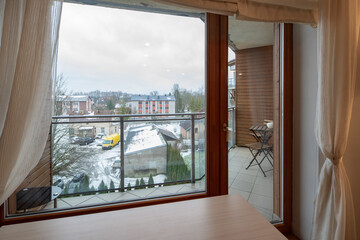 Modern interior of luxury apartment. Window and glass door to balcony. View of city.