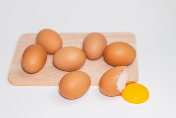 The yolk broke from the shell beside the wooden cutting board.