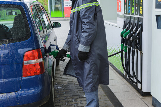 A gas station worker inserts a gas pistol into a car tank. Dolyna, Ukraine - May 12, 2020.