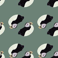ABstract tropic arctic animal seamless pattern with black and white colored puffin shapes. Pale blue background.