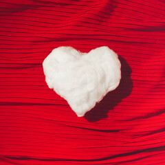 Handmade white fluffy heart on the red elegant drapery background. Flat Lay