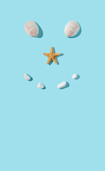 Creative smiley face made with sea shells, starfish and white rocks. Flat lay, minimal concept.
