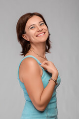 woman in a blue dress stands on a gray background. Shot in the studio
