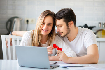 Loving couple in front of laptop monitor. Online meeting with friends on the eve of valentine's day.