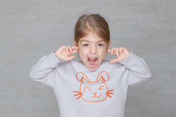 angry girl close cover ears with index finger.don't want to hear, naughty child, rebel kid concept.