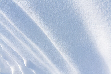 Winter season scene. Texture of snow waves in bright sunlight. With a natural surface. Copyspace template background of dunes and mountains of snowflakes