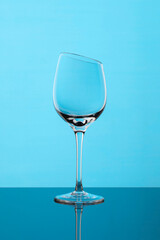 Glass wine goblet with beveled top edge on blue background