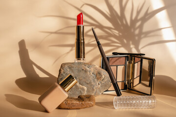 Makeup cosmetics in beige tones. Red lipstick, eye shadow, eyebrow pencil, foundation. The shadow...
