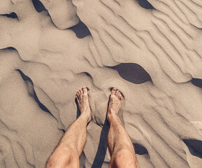 The traveler relaxes and rests with his bare feet on the warm sand. The concept of the hikes and the problems with orthopedics such as flat feet