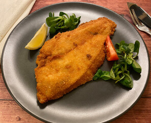 Golden breaded plaice fish fillet with lemon.