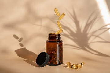 The pills fall into the jar. Levitation style. Omega 3 tablets on a beige background.