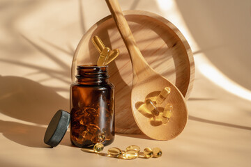 The pills fall into the jar. Levitation style. Omega 3 tablets on a beige background. Spoon with...