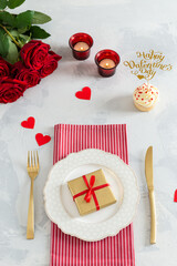 Romantic dinner concept. St Valentine's day or proposal background. Romantic gift on the white plate on restaurant table with hearts, roses and candles. Top view. Festive menu, 14 february