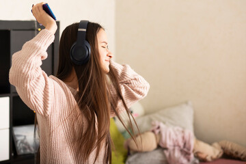 Teen girl at home dancing with headphones in her room