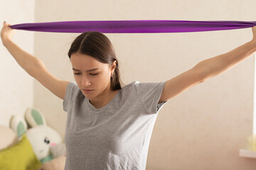 Sports at home during quarantine, the girl is engaged in fitness with an elastic band lifestyle