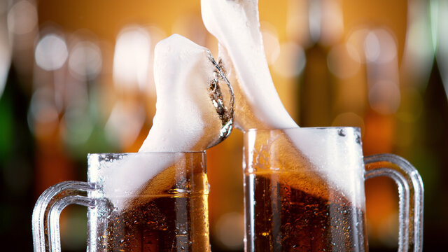 Pair of beer glasses with hand making a toast