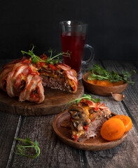 Minced meat baked in bacon. Meat pie with bacon on a dark wooden background.