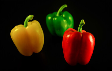 red green and yellow peppers on black background