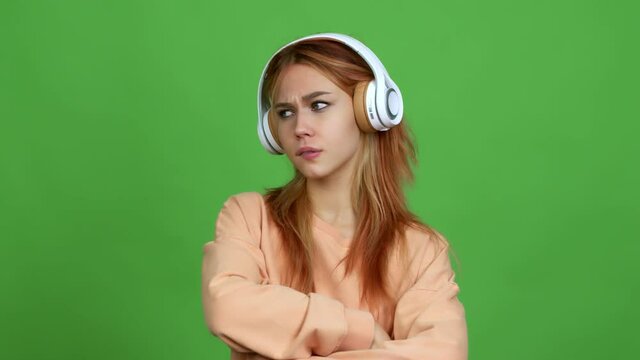 Teenager girl listening music with headphones having doubts and questioning an idea over isolated background