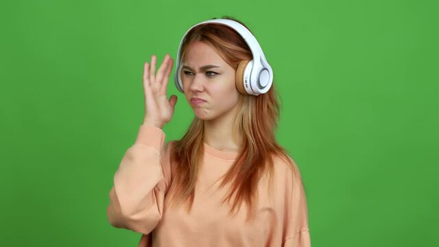 Teenager girl listening music with headphones having doubts while scratching head over isolated background